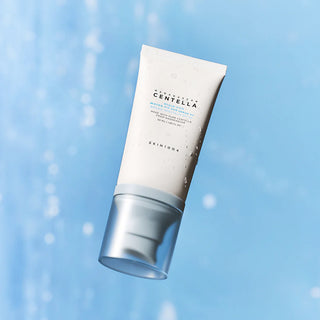 SKIN1004 Hyalu-Cica Sun Serum SPF50+ flottant en biais avec gouttelettes sur fond bleu ciel