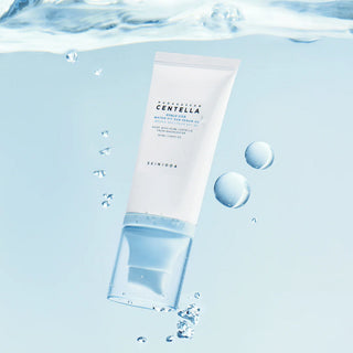 SKIN1004 Hyalu-Cica Sun Serum SPF50+ immerge dans l'eau avec bulles et gouttes sur fond bleu