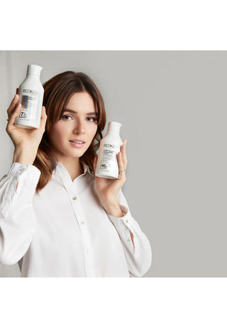 Modele brune tenant deux flacons Redken Acidic Bonding Concentrate shampooing et apres-shampooing
