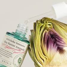 Flacon AXIS-Y Artichoke Ampoule posé contre un artichaut frais coupé en deux, tons verts et violets