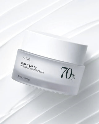 Pot blanc mat ANUA Heartleaf 70 Intense Calming Cream pose en biais sur fond de bandes de creme blanche