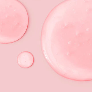 Gouttes roses translucides du serum ANUA Niacinamide 10+ TXA 4 sur fond rose pastel