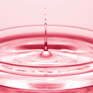 Goutte rose tombant dans un liquide rose creant des ondulations concentriques - serum ANUA Niacinamide