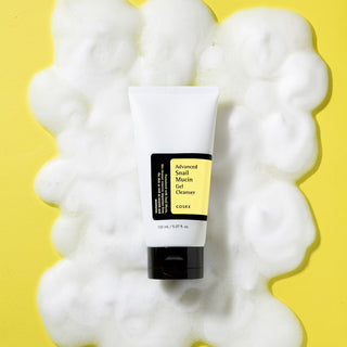 COSRX Nettoyant Gel Mucine Escargot tube blanc entouré de mousse sur fond jaune vif