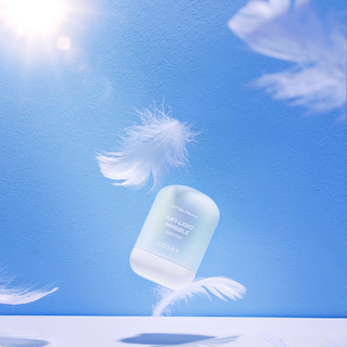 COSRX Airy-Light Invisible Sun Stick flottant avec plumes blanches sur fond ciel bleu