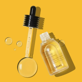 COSRX Propolis Light Ampoule flacon jaune ouvert avec pipette et gouttes dorees sur fond miel