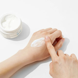 COSRX Hydrium Enriched Cream texture blanche etalee sur le dos de la main, pot ouvert a cote