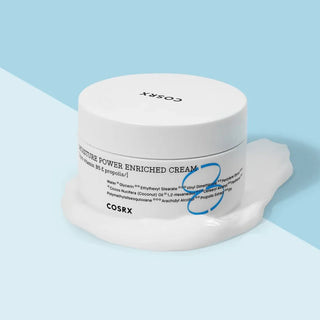 COSRX Hydrium Enriched Cream pot blanc sur fond bleu pastel avec touche de creme debordante