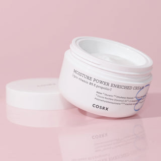 COSRX Hydrium Enriched Cream pot ouvert avec couvercle a cote sur fond rose pastel reflet miroir