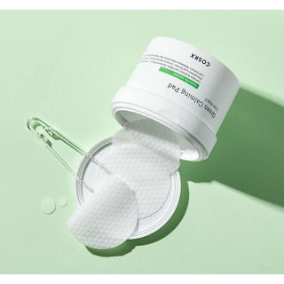 Pot COSRX Green Calming Pad retourne avec pads imbibes sortant du couvercle sur fond vert