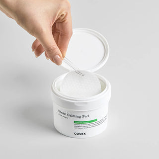 Main soulevant un pad texture gauffree avec pince depuis le pot ouvert COSRX Green Calming Pad