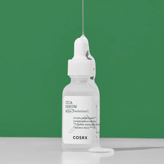 Flacon COSRX Pure Fit Cica Serum avec pipette et goutte de serum tombant sur fond vert