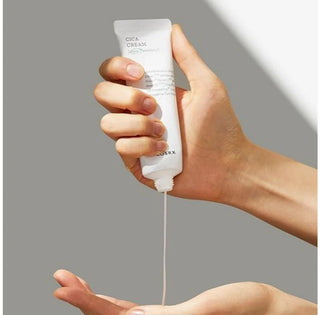 COSRX Pure Fit Cica Cream - main pressant le tube avec filet de creme qui coule