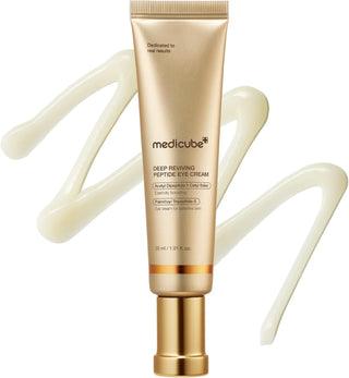 Tube dore MEDICUBE Deep Reviving Peptide Eye Cream avec texture creme en arriere-plan