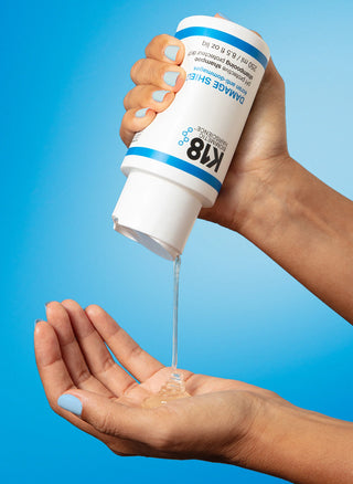 K18 Damage Shield shampoing protecteur pH verse sur la paume, texture gel translucide sur fond bleu