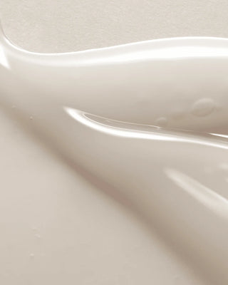 Texture cremeuse blanche du serum AXIS-Y Dark Spot Correcting Glow Serum en gros plan sur fond beige