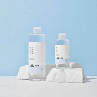 Round Lab 1025 Dokdo Toner - deux formats grand et petit poses sur des pierres blanches, fond bleu pastel