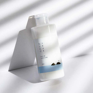 Round Lab Dokdo Lotion 1025 flacon translucide incline sur fond blanc avec ombres naturelles
