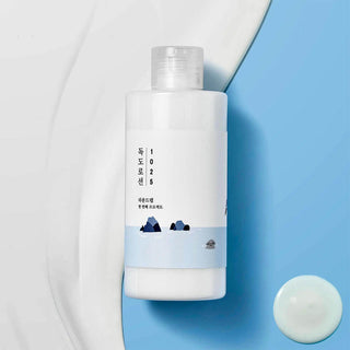 Round Lab 1025 Dokdo Lotion - flacon blanc sur fond bleu bicolore avec goutte de lotion a cote