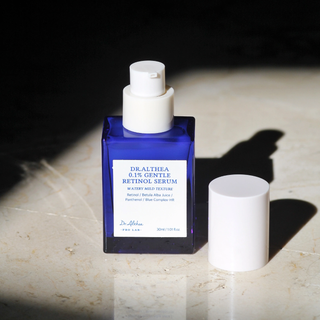 DR.ALTHEA Sérum Rétinol Doux 0,1% flacon bleu ouvert posé sur surface en marbre avec lumière naturelle