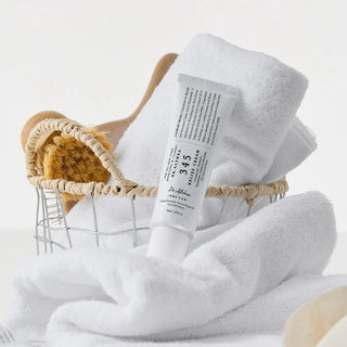 Tube DR.ALTHEA 345 Relief Cream dans un panier avec serviettes blanches et brosse en bois