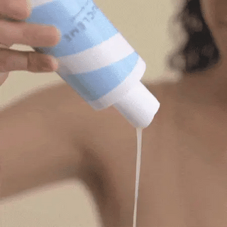 Application du shampoing Boucleme Hydrating Hair Cleanser verse dans la main depuis le flacon bleu