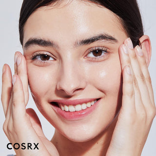 Visage souriant aux mains sur les joues montrant une peau hydratee et lumineuse avec COSRX