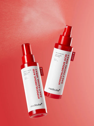Deux flacons MEDICUBE Hypochlorous Acid Daily Facial Spray sur fond rouge, l'un vaporise de la brume