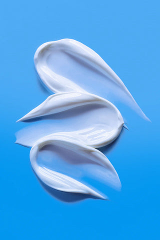 Texture onctueuse blanche de la TOCOBO Bio Watery Sun Cream en trois virgules sur fond bleu