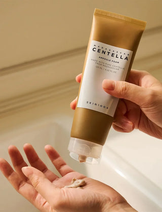 Mains pressant le tube SKIN1004 Centella Ampoule Foam, dose de mousse deposee dans la paume
