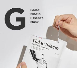 Main ouvrant le sachet ma:nyo Galac Niacin Essence Mask avec typographie bold sur fond gris