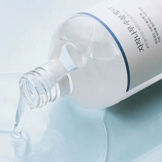 Round Lab Birch Juice Toner bouteille couchee versant une texture liquide transparente sur fond bleu clair