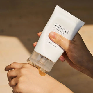 Main tenant le tube SKIN1004 Centella Soothing Cream et deposant une goutte de gel dore sur le poignet