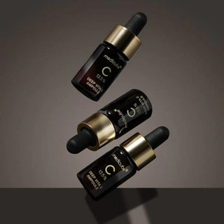 Trois flacons Medicube Deep Vita C Ampoule 2.0 noirs et dores avec pipette, en suspension sur fond sombre