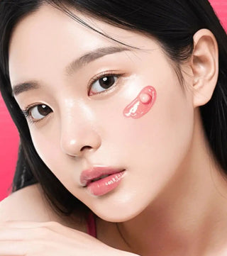 Gros plan visage avec capsule rose Medicube TXA Niacinamide ecrasee sur la joue, fond rose
