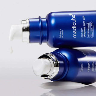 Deux flacons bleus Medicube Exosome Shot 2000 couches avec goutte de serum sortant de la pompe