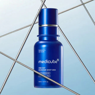 Flacon bleu Medicube Exosome Shot Pore 2000 devant des tiges metalliques sur fond bleu clair