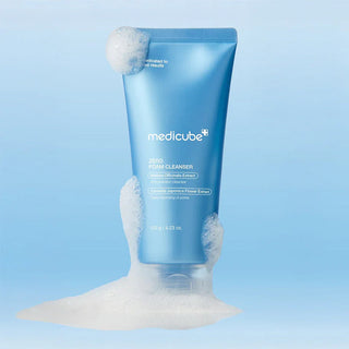 Tube Medicube Zero Foam Cleanser entoure de mousse blanche abondante sur fond bleu clair