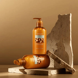 Nature Republic Argan Conditioner - deux flacons pompe ambres poses sur des dalles en pierre travertin
