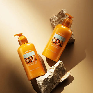 Nature Republic Argan Conditioner - deux flacons pompe ambres vus du dessus sur fond dore et pierres