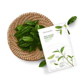 Sachet Nature Republic Green Tea pose a cote de feuilles de the vert fraiches sur un dessous de plat en osier