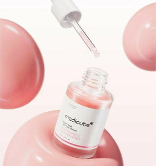 Flacon Medicube PDRN Pink Peptide Serum ouvert avec pipette et bulles roses flottantes