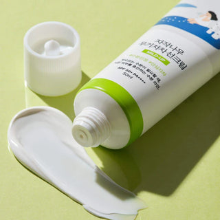 Round Lab Birch Mild-Up Sunscreen ouvert avec texture creme blanche onctueuse sur fond vert