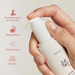 Main pressant la pompe du Beauty of Joseon Serum Solaire avec goutte de produit visible