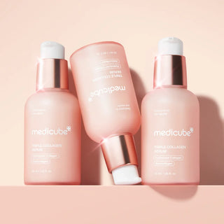 Trois flacons Medicube Triple Collagen Serum 4.0 roses disposes en groupe sur fond peche pastel