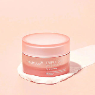 Pot rose Medicube Triple Collagen Cream ferme sur fond peche avec swatch de creme blanche a cote