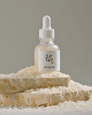 Beauty of Joseon Glow Deep Serum Rice pose sur des grains de riz blancs et pierres naturelles