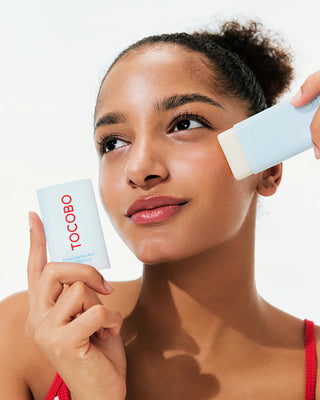 Modele appliquant le TOCOBO Cotton Soft Sun Stick sur la joue, baume visible sur la peau