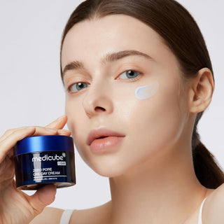 Modele tenant le pot Medicube Zero Pore One Day Cream, swatch de creme blanche appliquee sur la joue