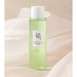 Beauty of Joseon Green Plum Refreshing Toner AHA BHA - flacon vert sur tissu satin rose